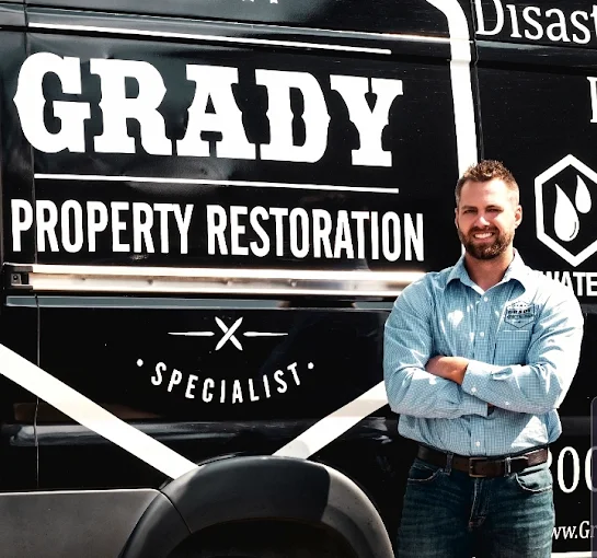 Bradley Grady standing beside a branded Grady Property Restoration response vehicle.